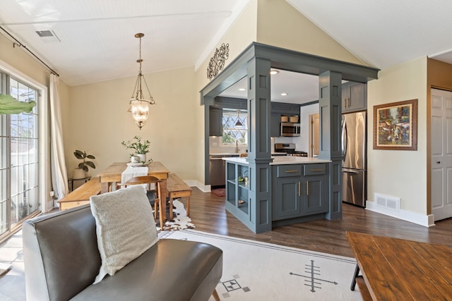 dining space featuring healthy amount of natural light, dark wood-style flooring, a chandelier, baseboards, and lofted ceiling