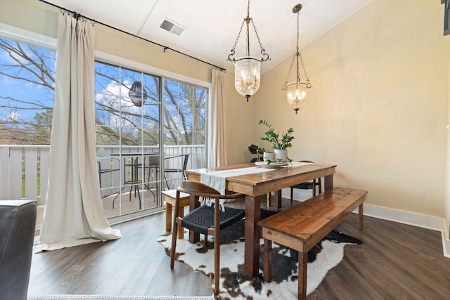 dining space featuring wood finished floors, a chandelier, baseboards, and lofted ceiling