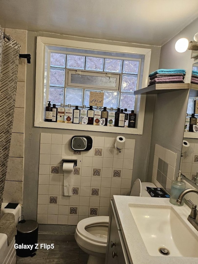 full bath with tile walls, plenty of natural light, vanity, and toilet