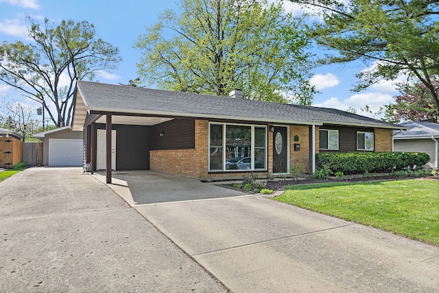 single story home with concrete driveway, brick siding, a front lawn, a chimney, and an outbuilding