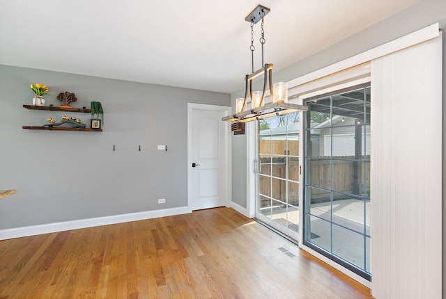 unfurnished dining area with baseboards and light wood-style floors
