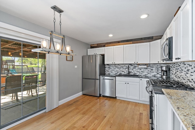 kitchen featuring stainless steel appliances, a sink, tasteful backsplash, white cabinets, and recessed lighting