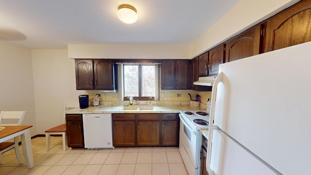 kitchen with under cabinet range hood, a sink, white appliances, and light countertops