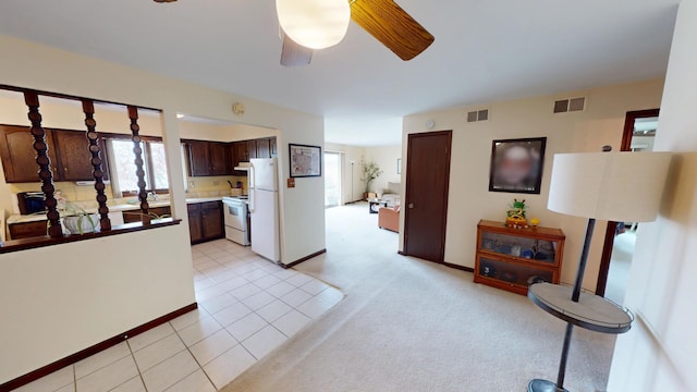 living room with ceiling fan, visible vents, light tile patterned floors, and a healthy amount of sunlight