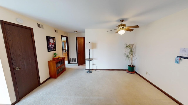 unfurnished room featuring light carpet, a ceiling fan, visible vents, and baseboards