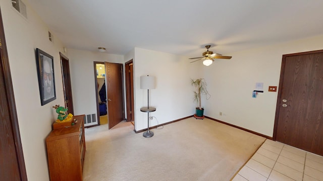spare room featuring light carpet, a ceiling fan, visible vents, and baseboards