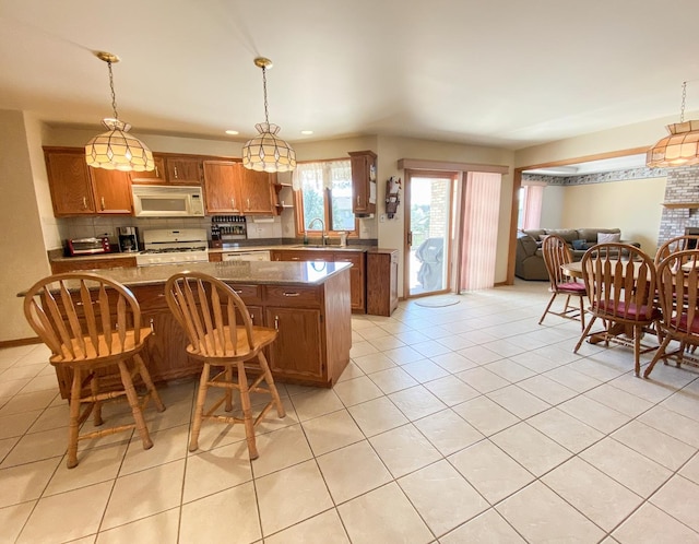 kitchen featuring recessed lighting, light tile patterned floors, a sink, white appliances, and brown cabinetry