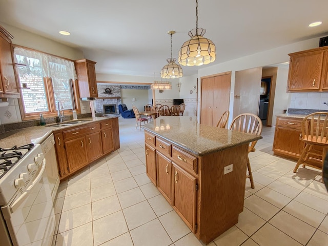kitchen featuring a kitchen breakfast bar, white appliances, a sink, and light tile patterned flooring
