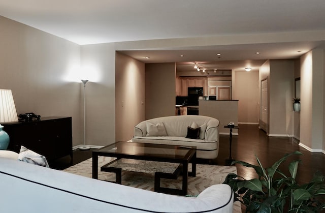 living room featuring track lighting, baseboards, and dark wood-style flooring