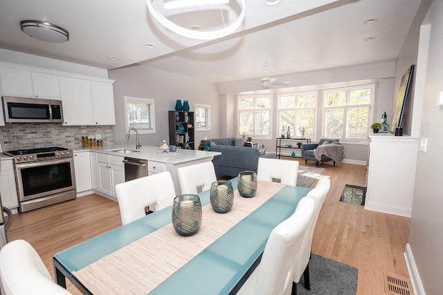 dining area with light wood finished floors, visible vents, baseboards, and a ceiling fan