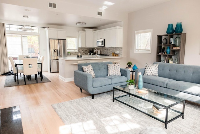 living room with a healthy amount of sunlight, light wood finished floors, and visible vents