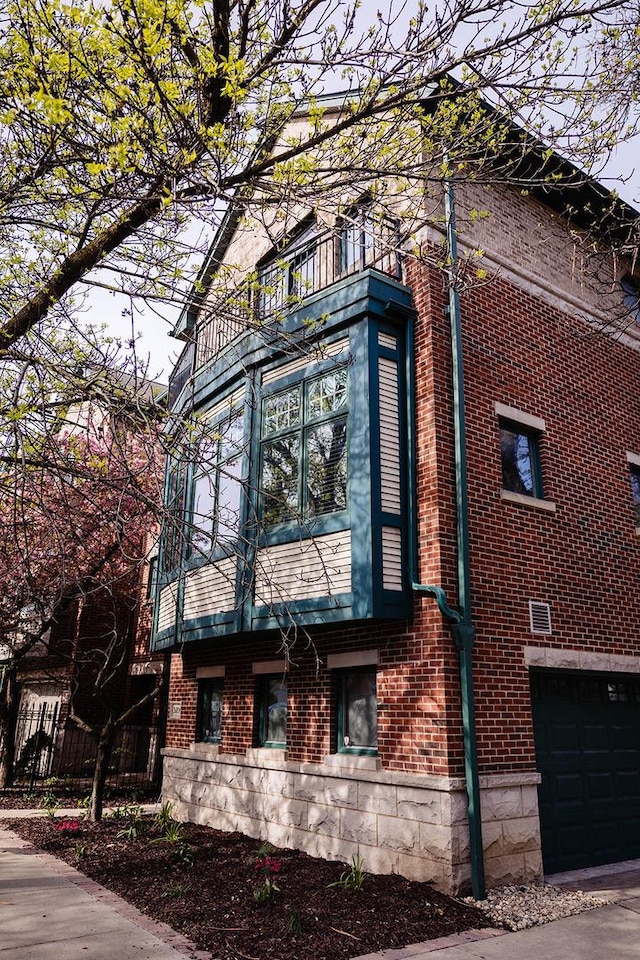 view of side of home with a balcony, brick siding, and a garage