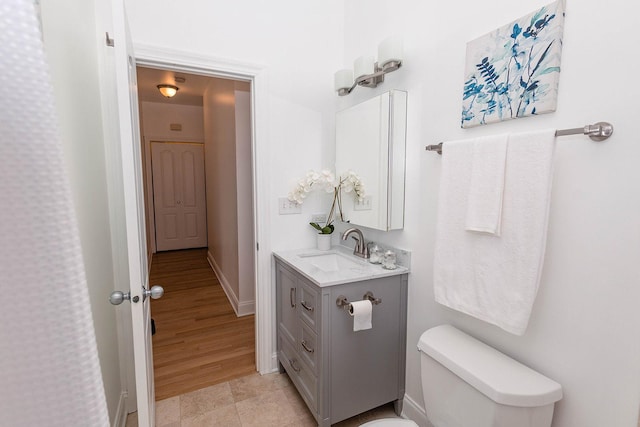 bathroom featuring toilet, baseboards, vanity, and wood finished floors