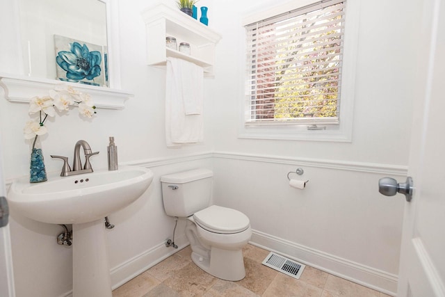 half bath featuring toilet, baseboards, and visible vents