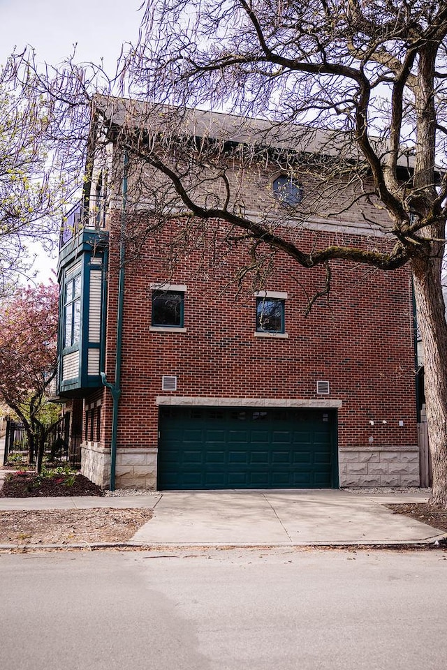 view of side of home with concrete driveway, brick siding, and a garage
