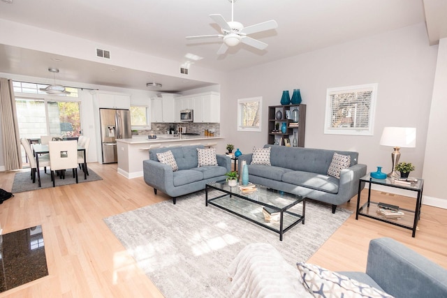 living area with ceiling fan, baseboards, visible vents, and light wood-style floors