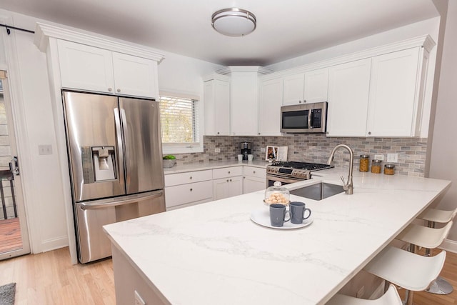 kitchen featuring light wood-type flooring, white cabinetry, appliances with stainless steel finishes, and a sink