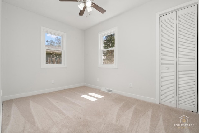unfurnished bedroom with a closet, visible vents, multiple windows, and baseboards