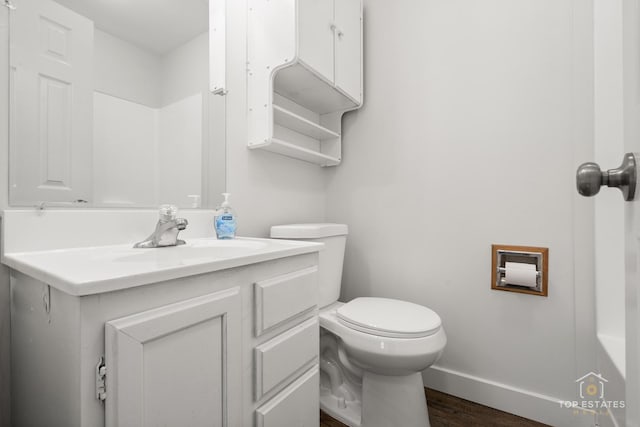 bathroom featuring baseboards, wood finished floors, toilet, and vanity