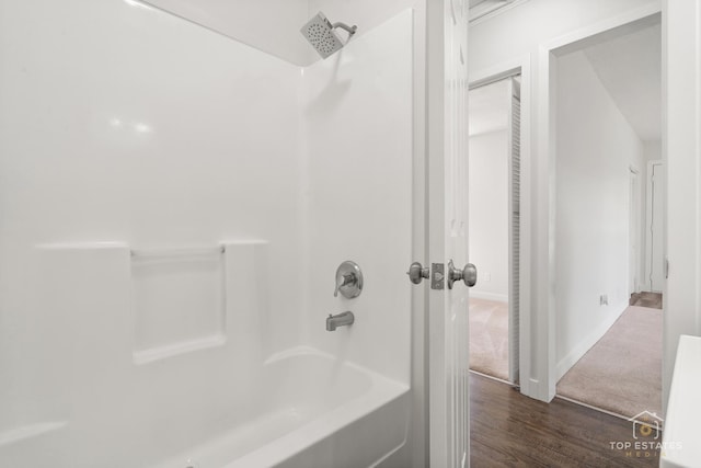 full bath with baseboards, wood finished floors, and shower / tub combination