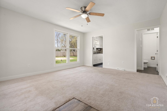 interior space featuring baseboards, visible vents, ensuite bath, and carpet floors