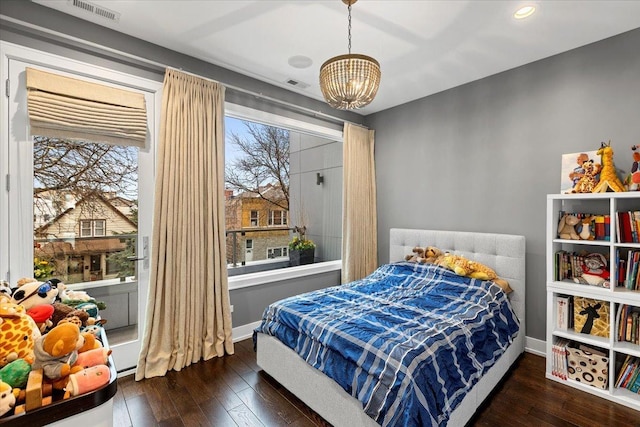 bedroom featuring wood-type flooring, a chandelier, visible vents, and baseboards