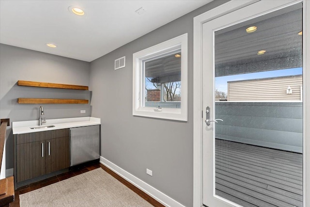 bar featuring baseboards, recessed lighting, dark wood-style floors, visible vents, and a sink