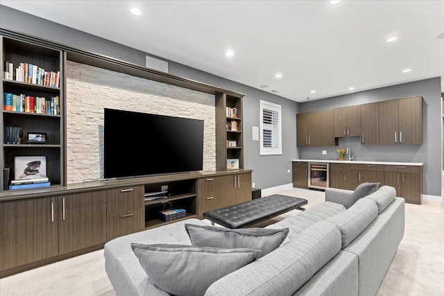 living room featuring beverage cooler, built in shelves, baseboards, and light carpet