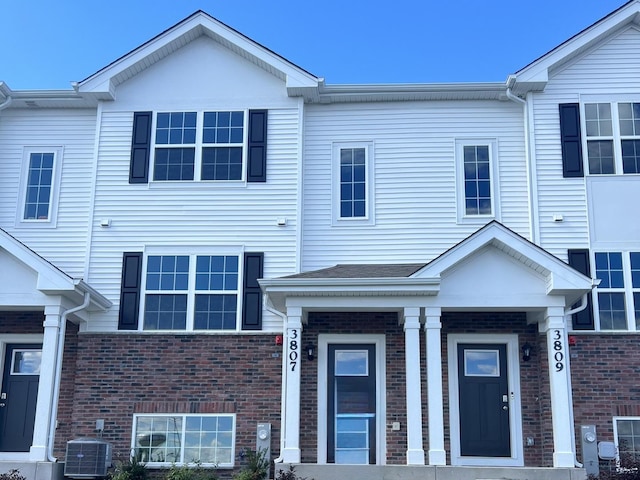 view of property with brick siding and central air condition unit