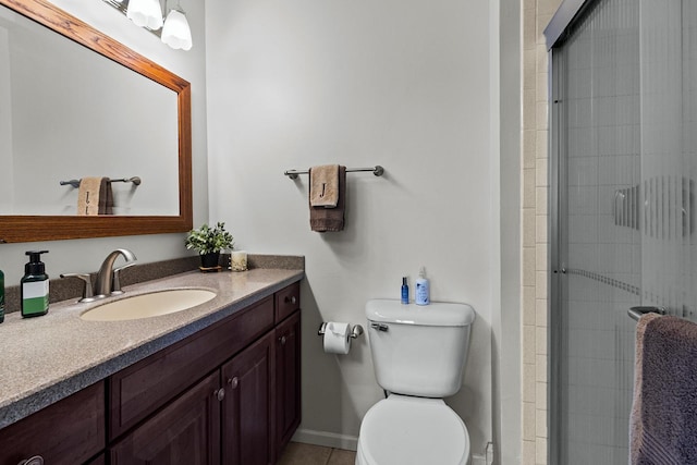 bathroom with a stall shower, baseboards, toilet, vanity, and tile patterned flooring