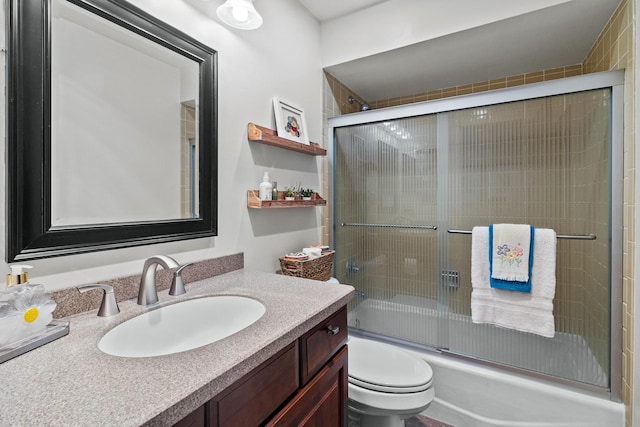 bathroom with toilet, enclosed tub / shower combo, and vanity