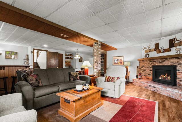 living area featuring ornate columns, visible vents, wood finished floors, and a fireplace