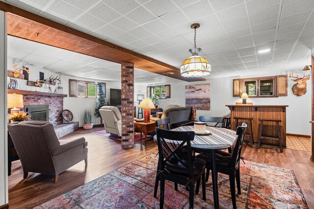 dining space featuring wood finished floors, a healthy amount of sunlight, and a brick fireplace