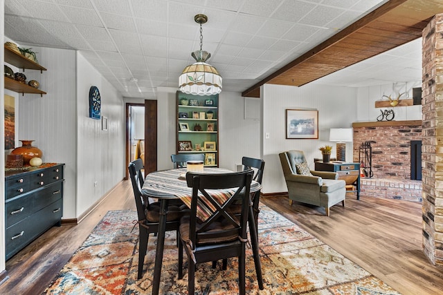 dining room with wooden walls, wood finished floors, and baseboards