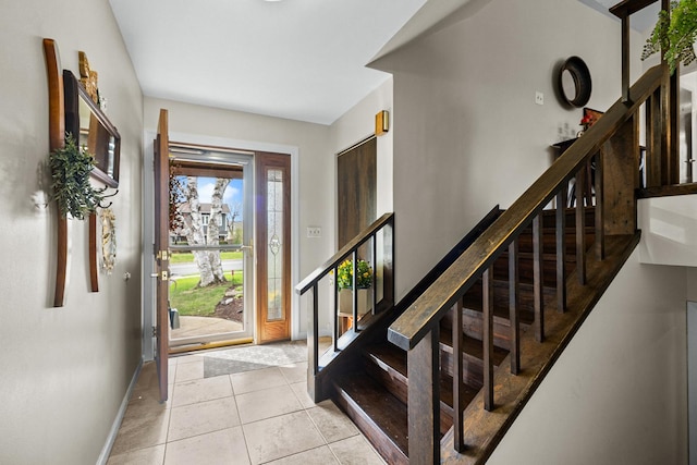 entryway with tile patterned flooring, stairs, and baseboards