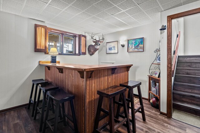 bar with baseboards, stairway, a bar, and dark wood-style flooring