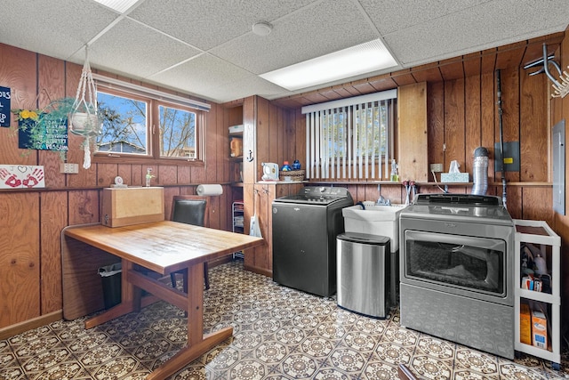 washroom featuring wooden walls, a healthy amount of sunlight, separate washer and dryer, and laundry area