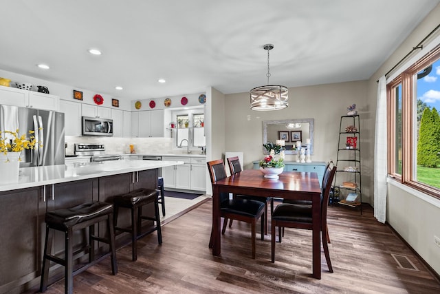 dining area featuring recessed lighting, a wealth of natural light, and dark wood-type flooring