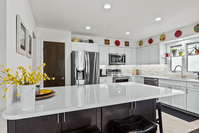 kitchen featuring a breakfast bar, a sink, stainless steel appliances, and decorative backsplash