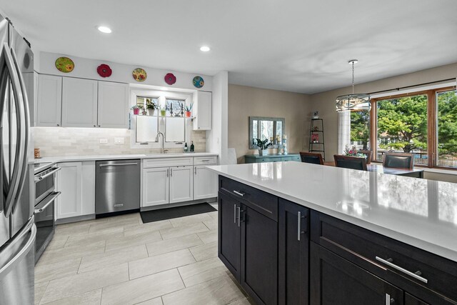 kitchen with a sink, a wealth of natural light, stainless steel appliances, and light countertops