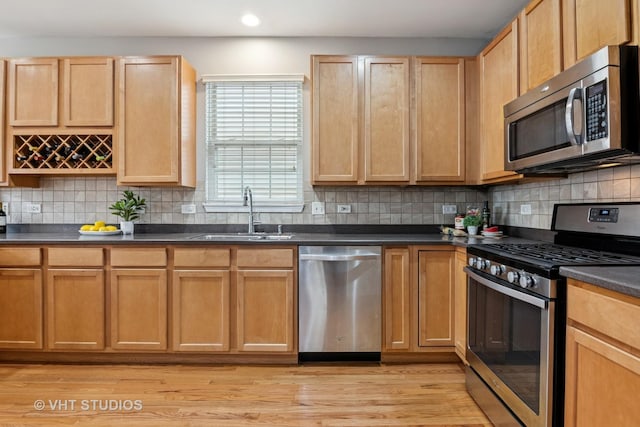 kitchen with dark countertops, a sink, recessed lighting, and appliances with stainless steel finishes