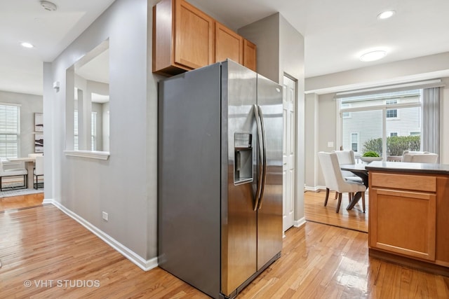 kitchen featuring light wood finished floors, plenty of natural light, and stainless steel fridge with ice dispenser