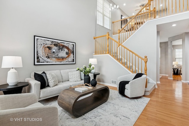 living room featuring baseboards, wood finished floors, visible vents, and stairs