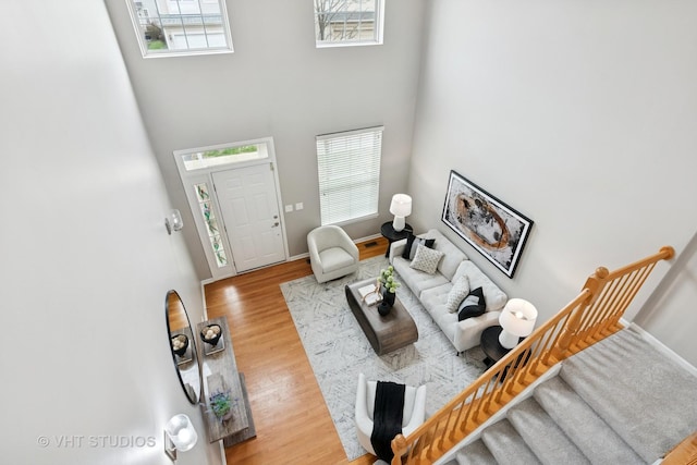 living area with baseboards, stairs, wood finished floors, and plenty of natural light