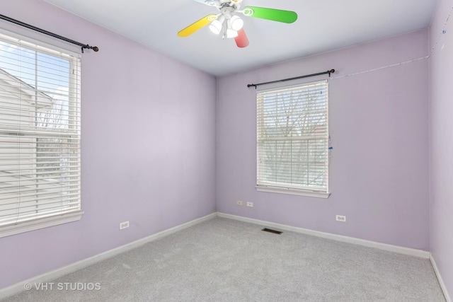 spare room with carpet, visible vents, a ceiling fan, and baseboards