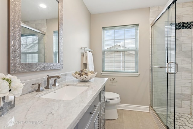 bathroom featuring a shower stall, vanity, toilet, and baseboards