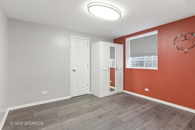 unfurnished bedroom with wood finished floors and baseboards