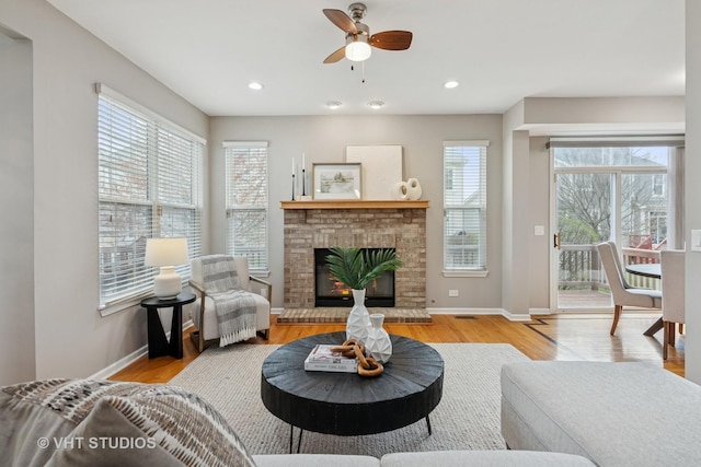 living area featuring recessed lighting, wood finished floors, a ceiling fan, baseboards, and a brick fireplace