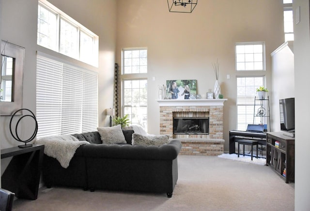 living room with carpet floors, a healthy amount of sunlight, a towering ceiling, and a fireplace
