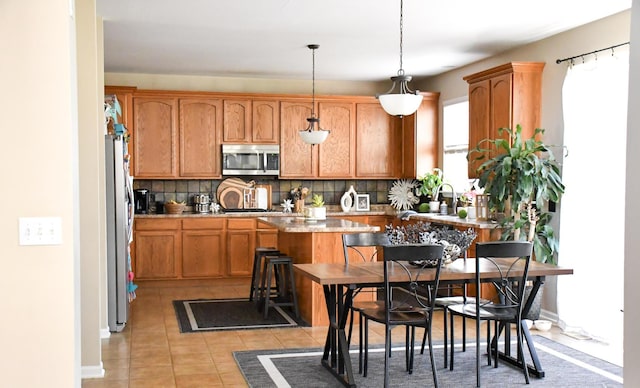 kitchen featuring decorative light fixtures, tasteful backsplash, appliances with stainless steel finishes, and light tile patterned floors